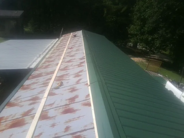 Old rusted panels beside newly installed green metal roofing — Wind Damage Roof Repair by Roofing Brothers in Christiana