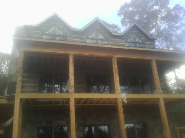 Dormers and porch framing on a large log home under construction — Roof Coating work by our crew in Christiana