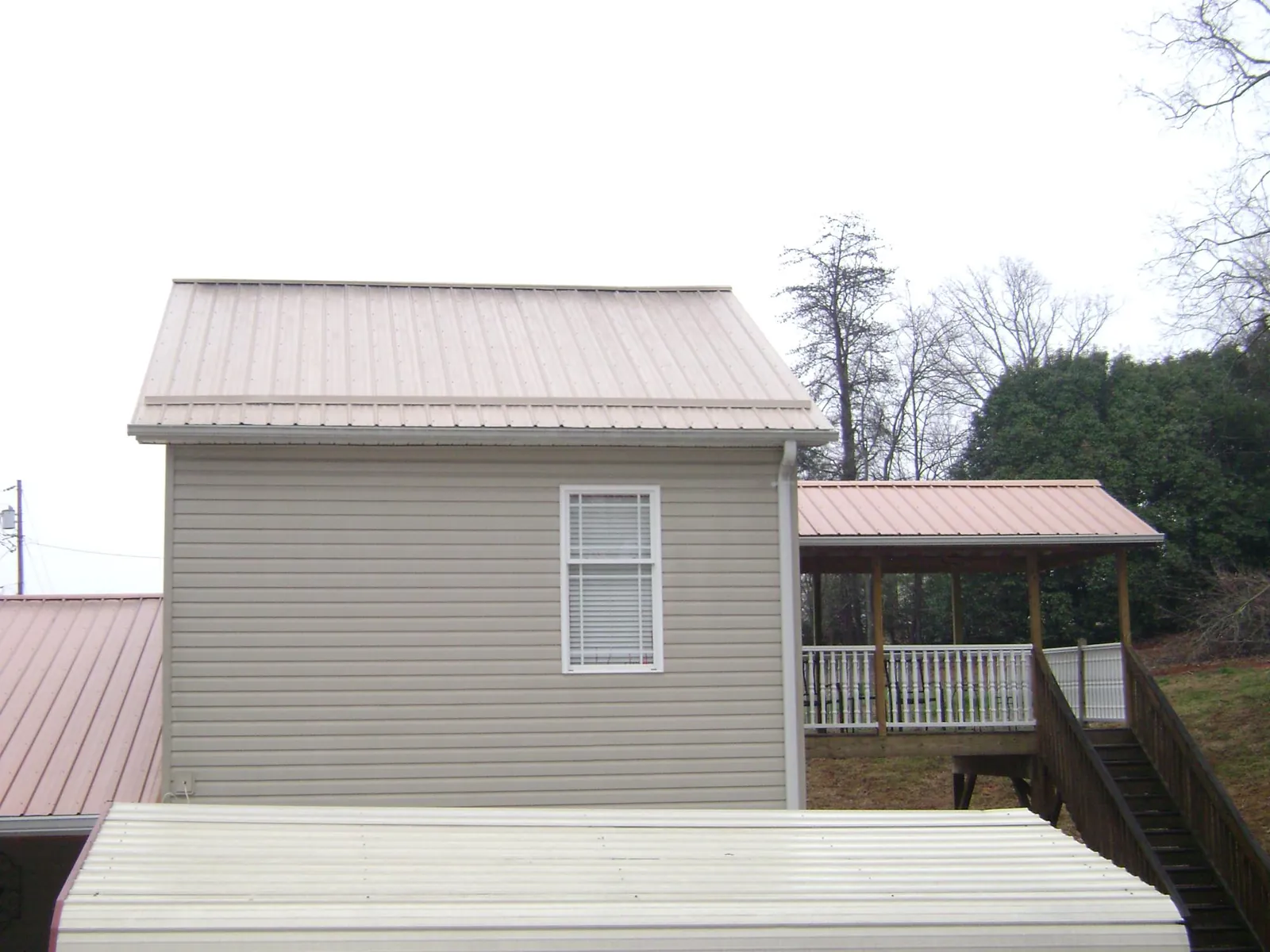 Tan metal roofs on a two story addition and attached porch in Christiana